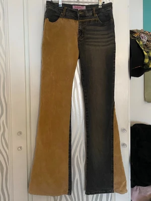 Tvåfärgade utsvängda jeans - Unika tvåfärgade jeans från Fishbone med ena benet i grå svart denim och det andra i brun/beihe manchester. Utsvängda ben, flared. 