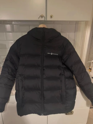 Sail Racing dunjacka – nyskick 🔥 - Stilren svart dunjacka från Sail Racing. Knappt använd och i perfekt skick, inga fläckar, märken eller skavanker. Fylld med kvalitetsdun (600 fill power) som ger grym värme utan att jackan känns tung.  ✔️ Tidlös design ✔️ Varm & lätt ✔️ Perfekt till höst och vinter  Storlek: 160 (motsvarar XS–S) beroende på hur du vill att jackan ska sitta men jag är 170cm och den passar bra tycker jag.  📦 Snabb frakt 💬 Hör av dig vid frågor eller fler bilder 