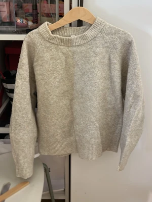 Ljusgrå stickad tröja från Uniqlo - Mysig ljusgrå stickad tröja från Uniqlo med rund halsringning och ribbade muddar vid ärmslut och nederkant. Enkel och stilren design som passar perfekt till lager på lager. Tillverkad i mjukt material för extra komfort.