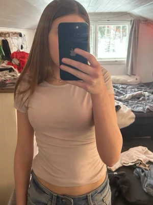 Ljusrosa tight t-shirt - En enkel och stilren ljusrosa t-shirt med tight passform och korta ärmar. Perfekt att matcha med jeans eller kjol för en clean look. T-shirten har rund halsringning och är gjord i ett mjukt material som känns skönt mot huden.