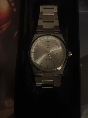 Tissot PRX silverfärgad klocka - Snygg Tissot PRX klocka i silver med stilren länk i rostfritt stål. Klockan har en rund urtavla med datumvisning och minimalistiska index. Perfekt accessoar för dig som gillar klassisk och tidlös design. Följer med Extender och batteri