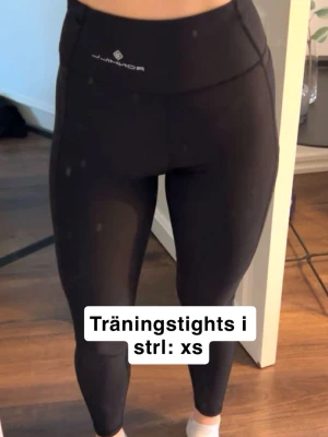 Svarta träningstights från Röhnisch - Snygga svarta träningstights från Röhnisch med hög midja och tight passform. Perfekta för gymmet eller löprundan. Materialet är stretchigt och följsamt för maximal rörelsefrihet.