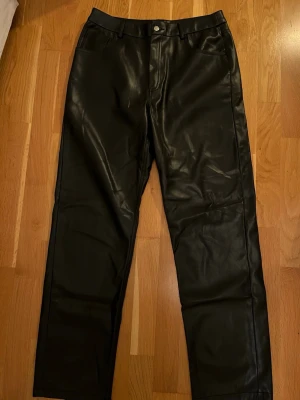Svarta skinnbyxor från Gina Tricot - Dessa snygga svarta skinnbyxor från Gina Tricot är perfekt till vardagen eller till festliga tillfällen. Modellen har en rak passform. Storlek 40