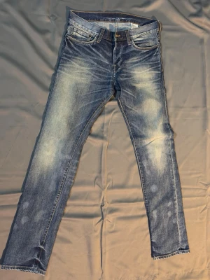 Slim fit jeans från H&M, blå - Säljer ett par blå slim fit jeans från H&M med låg midja och snygga slitningar. Jeansen har klassisk femficksmodell och är tillverkade i denim. Perfekta för en avslappnad och trendig look.