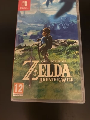 The Legend of Zelda: Breath of the Wild - Ett episkt äventyrsspel till Nintendo Switch där du utforskar en öppen värld som Link. Spelet kommer i ett plastfodral med färgstark omslagsbild och inkluderar spelkassett. Perfekt för dig som gillar fantasy och action.