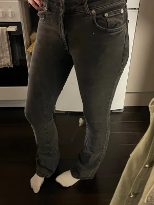 Mörkgrå raka jeans med hög midja - Säljer ett par mörkgrå jeans med raka ben och hög midja. Jeansen har klassiska fem fickor, silverfärgade nitar och knapp, samt bälteshällor. Perfekta för en avslappnad och trendig look.