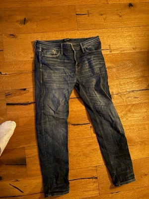 Blå slim fit jeans herr 33/32 - Snygga blå slim fit jeans med klassisk femficksdesign och lätt slitna detaljer. Jeansen har normal midja och smal passform hela vägen ner. Perfekta till en avslappnad streetstyle-look.