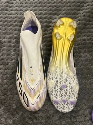 Adidas X Ghosted+ FG fotbollsskor - Säljer ett par Adidas X Ghosted+ FG fotbollsskor i vitt med guld- och svarta detaljer. Storlek 44 