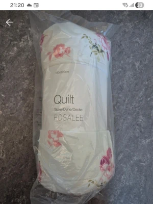 Quilt ROSALEE med blommönster - Quilt från ROSALEE i storlek 150x200 cm. Täcket är vitt med rosa och röda blommor samt gröna blad. Kommer i plastförpackning. Perfekt för att göra sängen extra mysig och dekorativ.