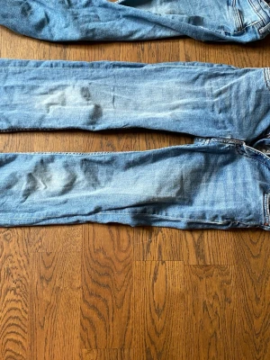 Ljusblå raka jeans - Säljer ett par ljusblå jeans med rak passform och klassisk femficksdesign. Jeansen har en något tvättad look och är tillverkade i denim. Perfekta för en avslappnad stil och passar till det mesta i garderoben.