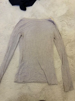 Ljusbeige intimisimi långärmad topp - En enkel och tunn ljusbeige långärmad topp med rund hals. Toppen har en smal passform och är tillverkad i ett mjukt material som känns skönt mot huden. Perfekt att styla lager på lager eller bära som den är. OBS den har ett hål i baksidan men det går säkert att laga