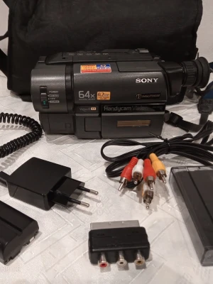 Sony Handycam videokamera med tillbehör - Säljer en svart Sony Handycam CCD-TRV16E videokamera med 64x digital zoom och 0.22 lux. Kameran är kompakt och har flera knappar och reglage. Medföljer laddare, kablar, SCART-adapter och väska. Perfekt för dig som vill filma med klassisk VIDEOKAMERA, bra för som vill digitalisera gamla video inspelningar datorn.           Ring vid frågor på 0700441696,   Kameran kan skickas, hämtas i Trollhättan eller i Göteborg