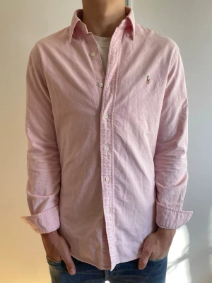 Rosa Ralph Lauren skjorta - Klassisk rosa Ralph Lauren skjorta som är i nyskick. Skjortan är använd max vid 2-3 tillfällen och har inga täcken på användning🤩 nypris:1599kr mot mitt pris 549kr✅ skjortan är perfekt inför våren och sommaren☀️ har du några frågor så är det bara att skriva och priset kan självklart diskuteras vid snabb och smidig affär👍😃