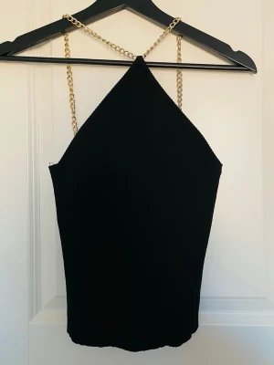 Topp/ linne fest/ sommar - Snygg svart ribbad linnetopp med band i guldfärgad kedja säljes. Aldrig använd.  Stl. xs/s