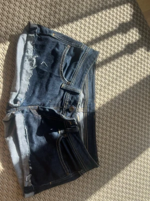 Mörkblå Lågmidjade jeansshorts  - Snygga mörkblå jeansshorts från pepe jeans med rå, fransig kant och klassiska fem fickor. Shortsen har kontrastsömmar och bälteshällor, perfekt för en avslappnad look. Gylf med knapp och dragkedja.