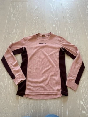 Rosa och vinrött underställ från Craft - Säljer ett underställ från Craft i rosa och vinrött. Setet består av en långärmad tröja och ett par tights, båda i ribbat funktionsmaterial som andas. Perfekt för träning eller utomhusaktiviteter under kallare dagar.