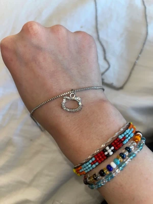 Silverfärgat hello Kitty halsband  - Snyggt silverfärgat halsband med en glittrig Hello Kitty-berlock dekorerad med små pärlor. Tunt och stilrent kedjearmband som passar perfekt för dig som gillar söta detaljer och vill ha något unikt på handleden.