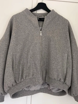 Grå bomberjacka från Zara - Jätte cool jacka från zara. Köptes förra året men är knappt använd. Den har en liten fläck(se bild), men det är inget man tänker på. Den är storlek L, men passar mig som brukar ha s/xs i jackor. 