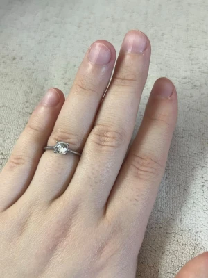 Silverring med klar sten - Stilren silverfärgad ring med en gnistrande klar sten i solitärfattning. Ringen har en tunn, rund skena och stenen är fyrkantigt slipad vilket ger en modern och elegant look. Perfekt för dig som gillar minimalistiska smycken med lite extra bling.