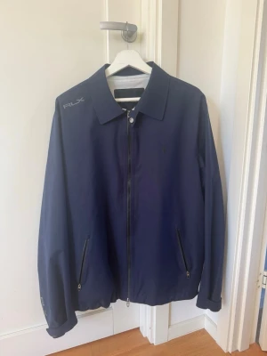 Mörkblå Ralph lauren jacka - Snygg mörkblå vindjacka från RLX Ralph Lauren med hel dragkedja framtill. Använd fåtal gånger bara att höra av sig vid frågor! Pris kan diskuteras vid snabb affär. Köpt för 2500kr