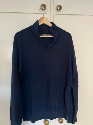 Mörkblå halvzip-tröja från dressmann - Klassisk mörkblå stickad tröja från dressmann med halv dragkedja och hög krage. Perfekt för lager på lager och stilren look.