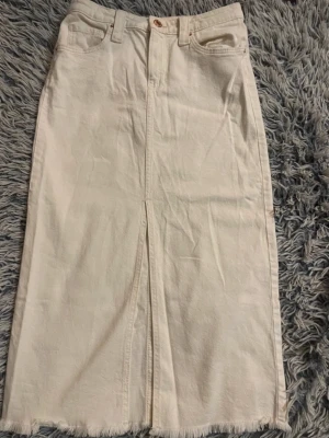 Vit långkjol i denim med slits - Snygg vit långkjol i denim med rå kant nertill och slits framtill. Kjolen har klassiska jeansdetaljer som fickor och bälteshällor. Perfekt för dig som gillar en clean och stilren look. Pris kan såklart diskuteras!💕