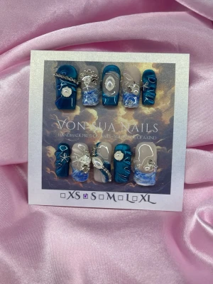 BlueMyth (S);Medium Square;Curved - Unika handgjorda press-on naglar i blåcateye, vit/blå french och nude. Naglarna har en mix av design och glansiga ytor, dekorerade med silverkedjor, pärlor och handmålade 3D-mönster. Formen är medium square och i storlek . Perfekt för dig som vill sticka ut med coola detaljer.