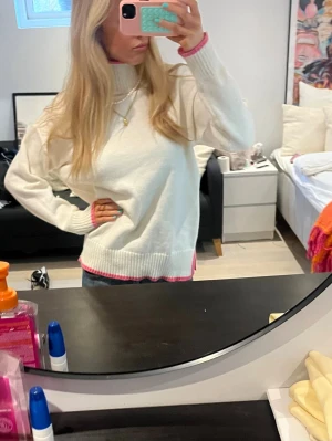 Vit stickad tröja med rosa detaljer - Säljer den populära stickade polotröjan med rosa detaljer från meet me there med Filippa montans kollektion, använt bara få få gånger!