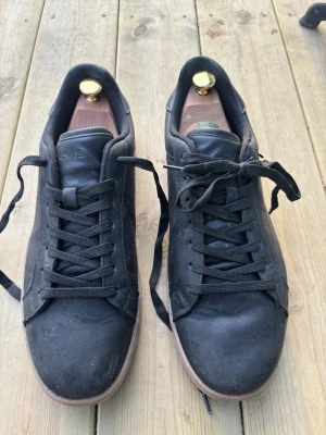 Svarta Levis sneakers i läder - Stilrena svarta sneakers från Levis med ovandel i läder och klassisk låg profil. De är i väldigt bra skick och används fåtal gånger