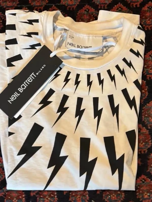 Neil barret t shirt - Stilren tischa ifrån märket Neil Barett i storlek S. Passar runt 170-180 cm. Jag är 180 cm 70 kg och då sitter den som ”muscle fit”. Den är lite använd men inga defekter. På bilden är lappen där men den har slarvats bort tyvärr. Hör av er vid frågor och funderingar!