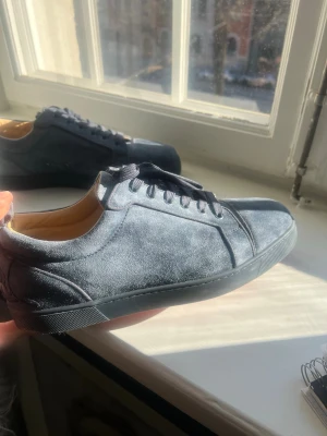 Mörkblå Loubs  - Snygga mörkblå sneakers i mocka med matchande mörkblå snörning och röd sula. Skorna har en stilren och minimalistisk design med lågt skaft och ljusbrunt innerfoder. 