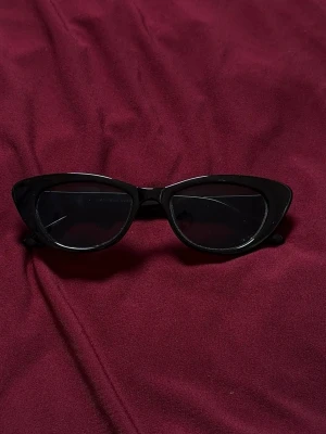 Svarta cat eye solglasögon - Snygga svarta cat eye solglasögon med glansig finish och markerad båge. Klassisk retrostil som ger en cool vibe till din outfit. Tillverkade i syntetmaterial och passar perfekt för soliga dagar.