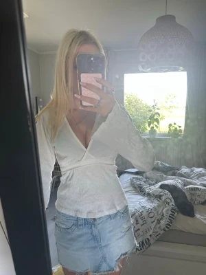 Ljusblå jeansshorts med rå kant - Säljer ett par ljusblå jeansshorts med rå, fransig kant och klassisk femficksdesign. Shortsen har en midwaist passform och är perfekta för sommaren. Snygga detaljer med slitningar och ljus tvätt för en avslappnad look.