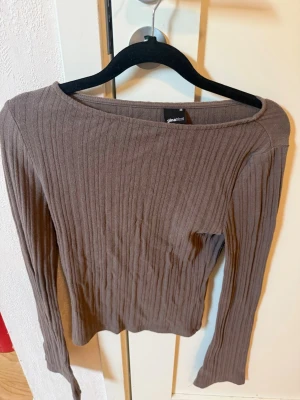 Brun ribbstickad tröja Gina Tricot - Säljer en brun ribbstickad tröja från Gina Tricot med lång ärm och rundad halsringning. Tröjan har en smal passform och är tillverkad i ett mjukt, stretchigt material som sitter snyggt på kroppen. Perfekt till jeans eller kjol.