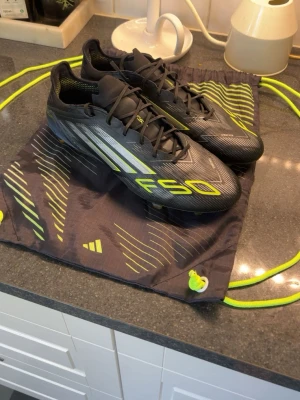 Adidas F50 elite - Snygga svarta Adidas F50 fotbollsskor med  grön och vita detaljer. Skorna har låg profil, snörning och en lätt ovandel i syntetmaterial för bra bollkontroll. Perfekta för dig som vill ha snabbhet och stil på planen.