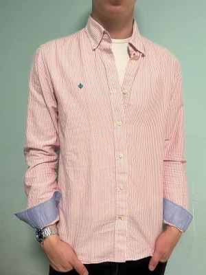 Morris skjorta rosa/vit randig – 39/40 (M) - Säljer en stilren rosa/vit randig skjorta från Morris i storlek 39/40 (M). Passar lika bra till vardag som till mer uppklädda tillfällen. I mycket fint skick.  Har du frågor? Tveka inte att höra av dig. Allt gott från Deluxe garderoben ⭐️