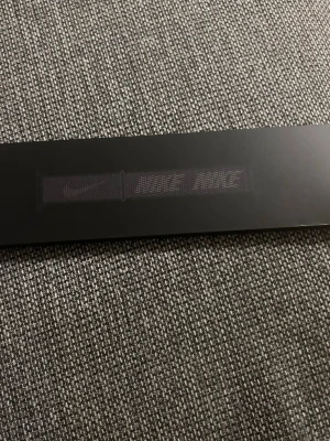 Apple Watch Nike Sport Loop – 45mm - Nike Sport Loop armband till Apple Watch i svart. Tillverkat i mjukt och ventilerande nylonmaterial med kardborrestängning. Armbandet har en sportig design med Nike-logga och är justerbart för bästa passform. Perfekt för dig som vill ha en snygg och funktionell wearable-accessoar.                                           Passar Apple Watch 42/44/45mm