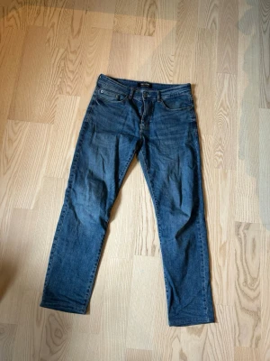 Mörkblå raka jeans - Snygga mörkblå jeans med rak passform och klassisk femficksdesign. Jeansen är raka och är tillverkade i denim. Perfekta för en avslappnad och stilren look.
