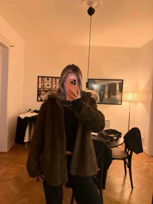 Brun pälsjacka med huva - Säljer en brun pälsjacka i mjukt fuskpälsmaterial. Jackan har en rak passform och är perfekt för kalla vinterdagar. Enkel att matcha med olika outfits och ger en lyxig känsla. Stängs framtill och har långa ärmar.