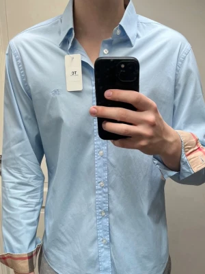 Burberry skjorta - Super snygg ljusblå  burberry i skjorta storlek M, skjortan är i super bra skick utan några defekter. Nypris runt 5000kr mitt pris endast 1000kr! Hör av er vid frågor. Mvh Trend closet🙌🌊