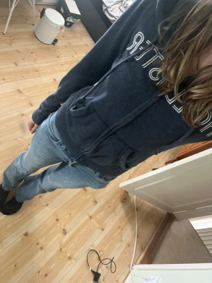 Hollister - Mörkblå hoodie från Hollister med dragkedja framtill och stor vit logga över bröstet. Tröjan har huva, två fickor fram och ribbade muddar vid ärmslut och nederkant. Perfekt för en avslappnad och cool stil. Säljs då jag behöver få lite pengar till min hund🙈 Inga defekter hittade! Skriv vid frågor!!❤️Storleken är XS men passar XS-S💕