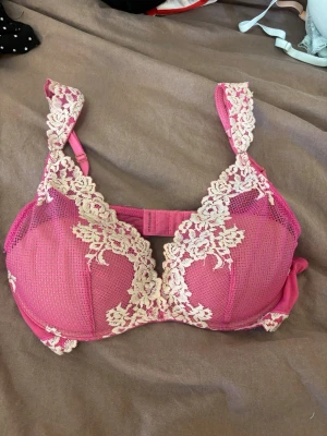 Rosa spets-bh från Intimissimi - Säljer en snygg rosa bh från Intimissimi med vacker vit spetsdetalj över kuporna och axelbanden. Bh:n har vadderade kupor och justerbara axelband. Perfekt för dig som gillar feminina och romantiska underkläder. I storlek 75 b