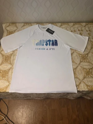 Vit Trapstar t-shirt med broderi - Trapstar T-shirt – Vit/Blå (Strl M) Säljer en snygg och populär Trapstar T-shirt i vit färg med blå/vit logga. Helt ny med tags kvar. • Storlek: M (normal passform) • Skick: Helt ny med tags • Färg: Vit med blå/vit logga • Stilren och eftertraktad design • Mycket populär modell som säljs betydligt dyrare online Perfekt för dig som vill ha en exklusiv Trapstar T-shirt till ett bra pris. Först till kvarn.