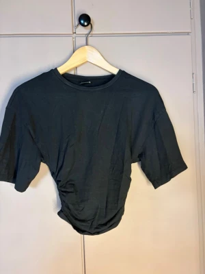 Svart t-shirt från Gina Tricot - En basic svart t-shirt från Gina Tricot i mjuk bomull. Modellen har rund halsringning och korta ärmar, perfekt att styla till jeans eller kjol för en clean look.