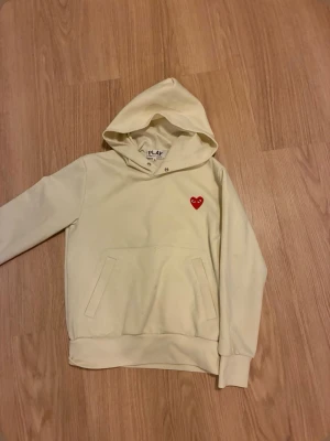 Vit hoodie Comme des Garçons Play - Säljer en stilren vit hoodie från Comme des Garçons Play med det ikoniska röda hjärtat på bröstet. Hoodien har huva, magficka och ribbade muddar. Tröjan är i storlek S. Hör av er vid frågor😊