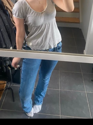 topp Odd Molly - Supersöt grå topp från Odd Molly med diskreta ränder och korta ärmar. Klänningen har u-ringning med liten rosett framtill och är gjord i mjuk bomull. 