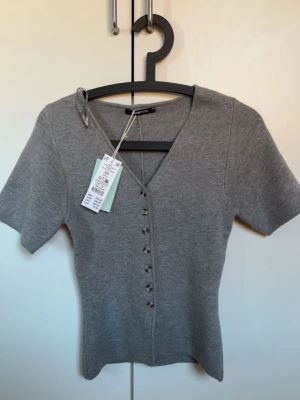 Grå topp  - Grå topp från gina, nypris 399. Aldrig använd, prislappen kvar. 
