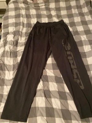 Svarta träningsbyxor från gasp - Säljer ett par svarta träningsbyxor från gasp  med resår i midjan och tryckt logga längs ena benet. Byxorna har raka ben och är tillverkade i ett lätt och bekvämt material som passar perfekt till gymmet eller löprundan.