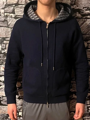 Christian Di9r Zip Hoodie - Säljer en fet mörkblå zipper med feta detaljer på insidan. Tröjan är perfekt för sommaren men även till vintern. Passar varje outfit. Endast seriösa köpare. Denna tröja finns knappt på Plick. Ej använd. Materialet e tjock o hållbar