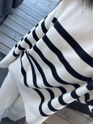 Randig stickad tröja i offwhite och marinblå - Säljer en oversized stickad tröja i offwhite med breda marinblå ränder. Tröjan har rund halsringning, långa ärmar och ribbade muddar. Perfekt för en avslappnad och trendig look. Materialet känns mjukt och bekvämt.